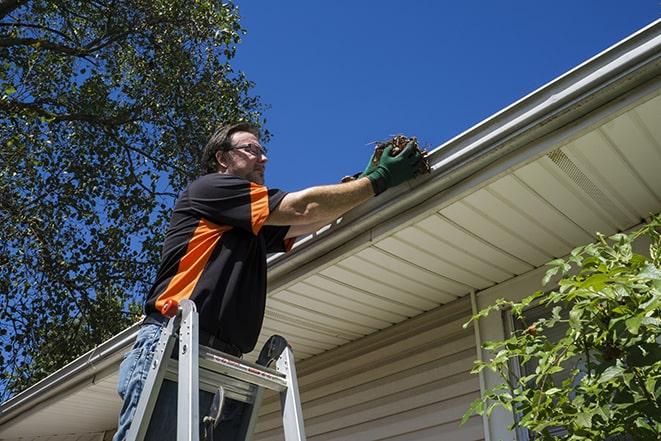 home renovation worker replacing broken gutter sections in Malden MA